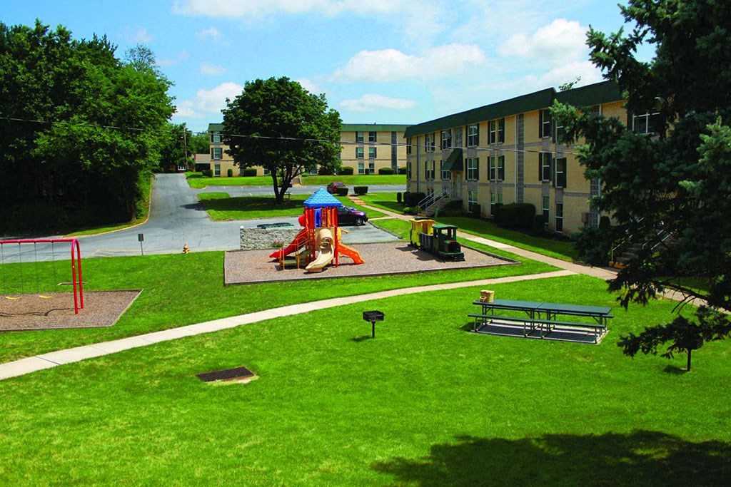 a playground in a park in front of an apartment building