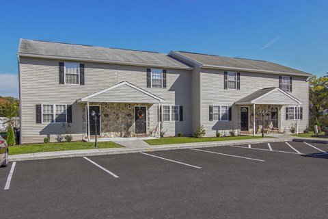 A large grey building with a parking lot in front.