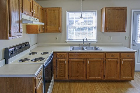 A kitchen with wooden cabinets and a stove top oven.
