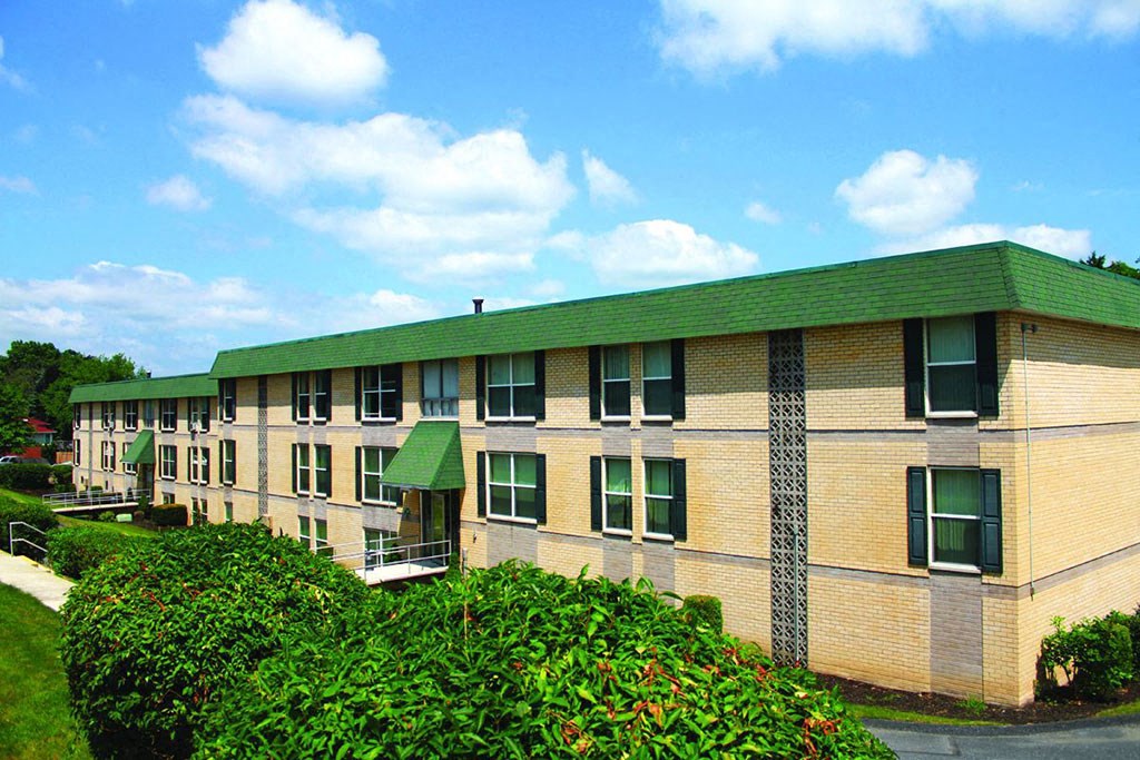 a building with a green roof and some bushes