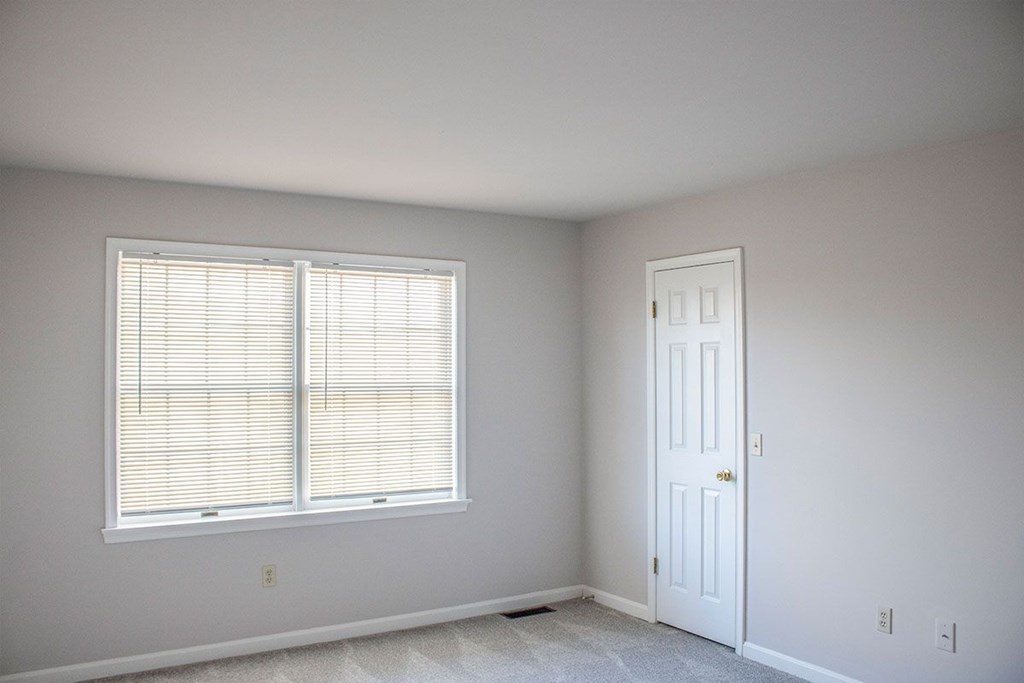 A room with a white door and a window with blinds.