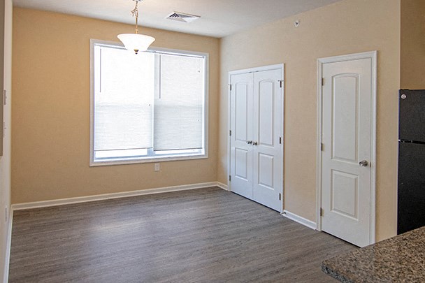an empty living room with white doors and a window