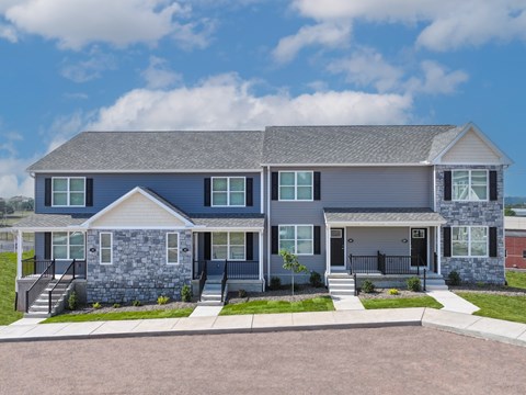 A two-story house with a grey roof and a stone foundation.
