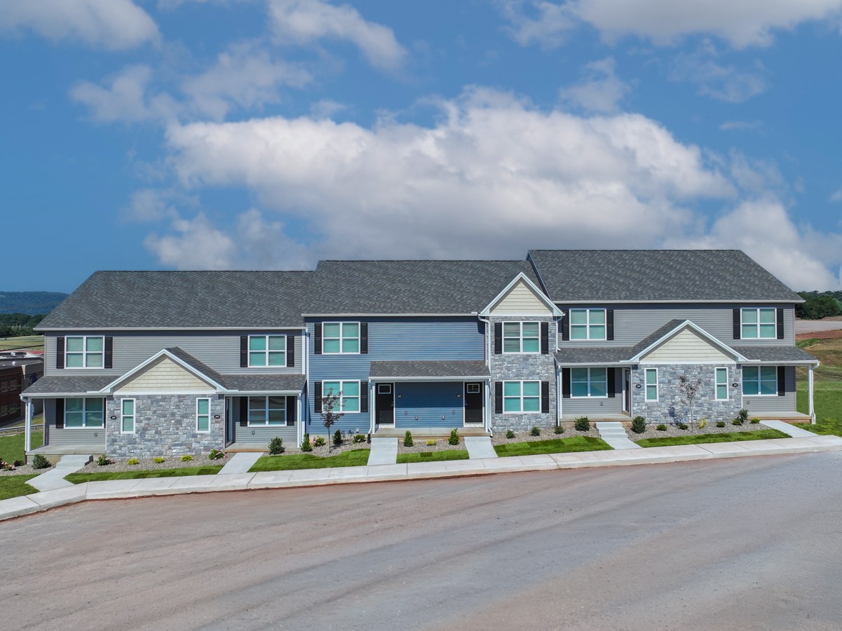 A large house with a grey roof and a stone wall.