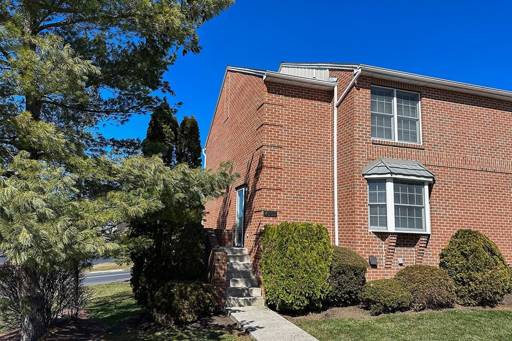 A red brick house with a tree in front.