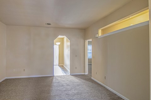 A spacious room with carpeted flooring and white walls.