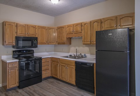 A kitchen with wooden cabinets and black appliances.