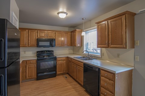 A kitchen with wooden cabinets and black appliances.