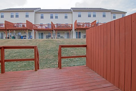 A wooden deck with a red fence in front of a white building.