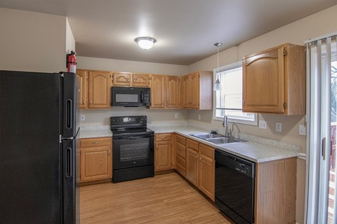 A kitchen with wooden cabinets and black appliances.