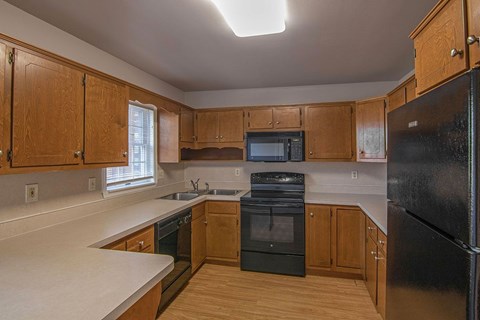 A kitchen with wooden cabinets and black appliances.