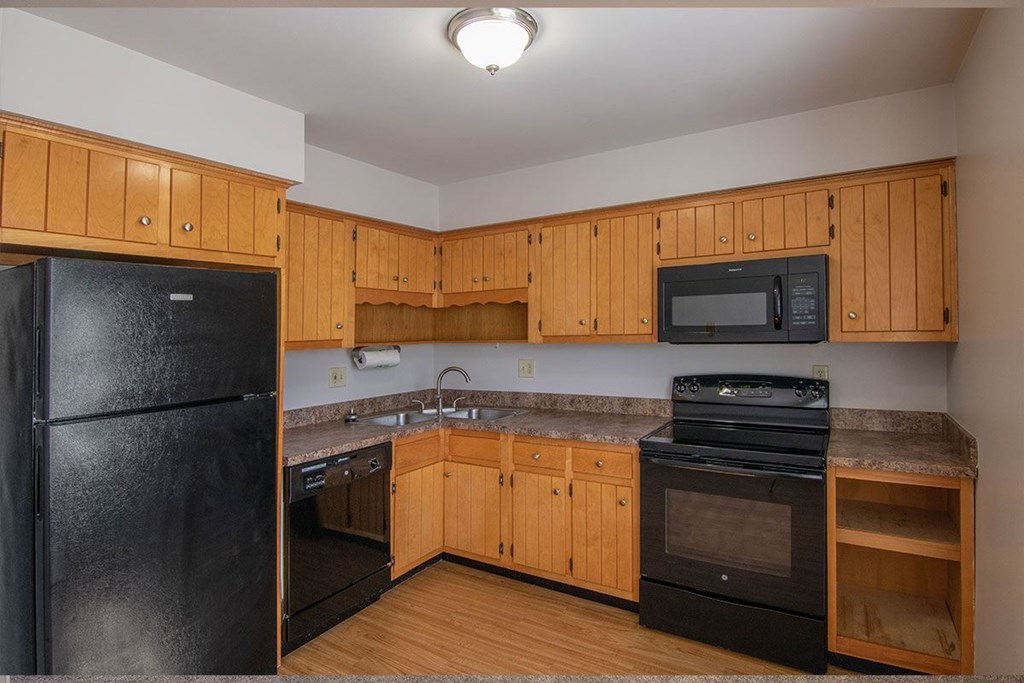 A kitchen with wooden cabinets and black appliances.