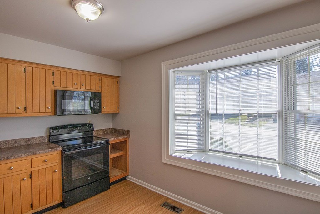 A kitchen with wooden cabinets and a black oven.