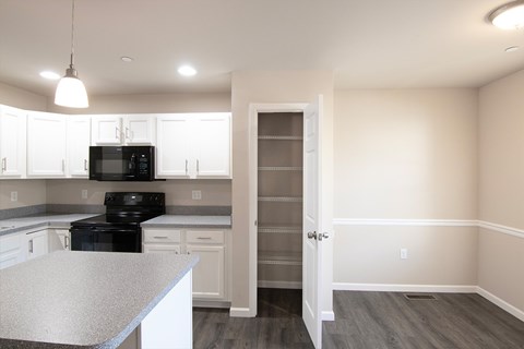 A kitchen with white cabinets and a black microwave.