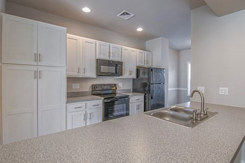 A kitchen with white cabinets and a granite countertop.