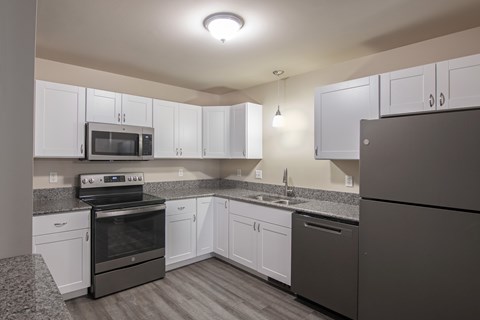 A kitchen with white cabinets and a black refrigerator.