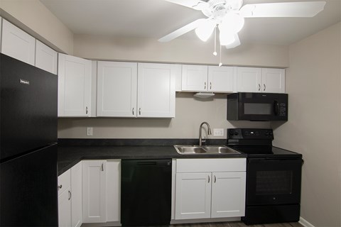 A kitchen with black appliances and white cabinets.