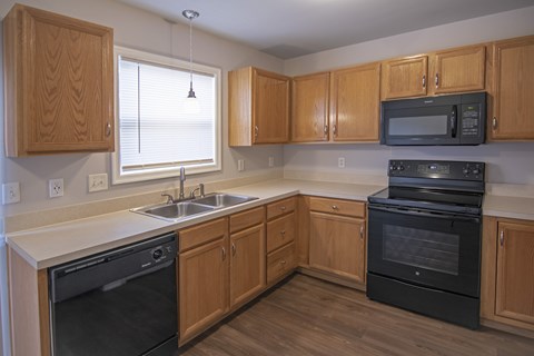 A kitchen with wooden cabinets and black appliances.