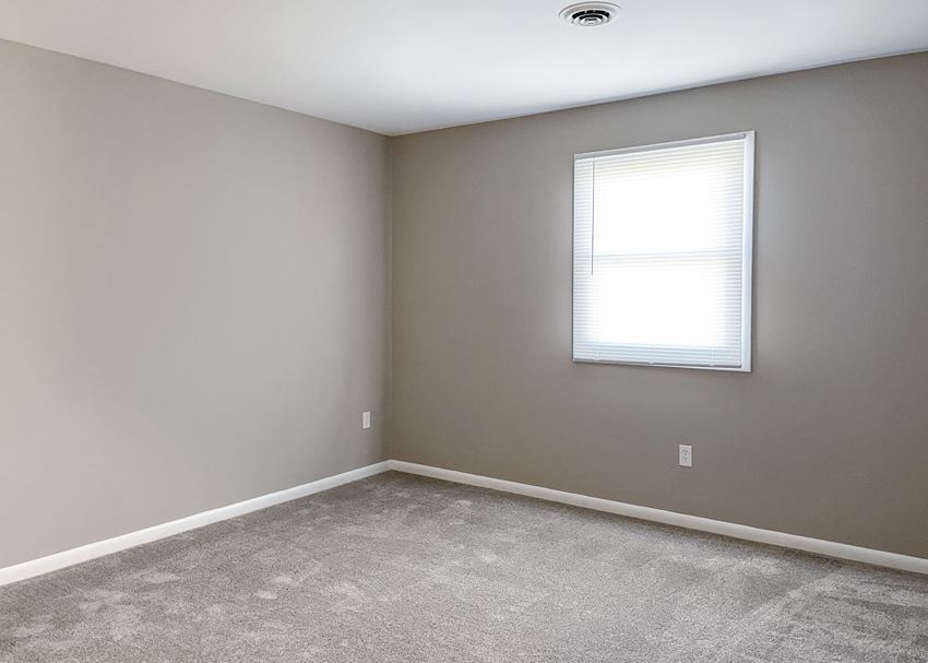an empty room with a window and carpet
