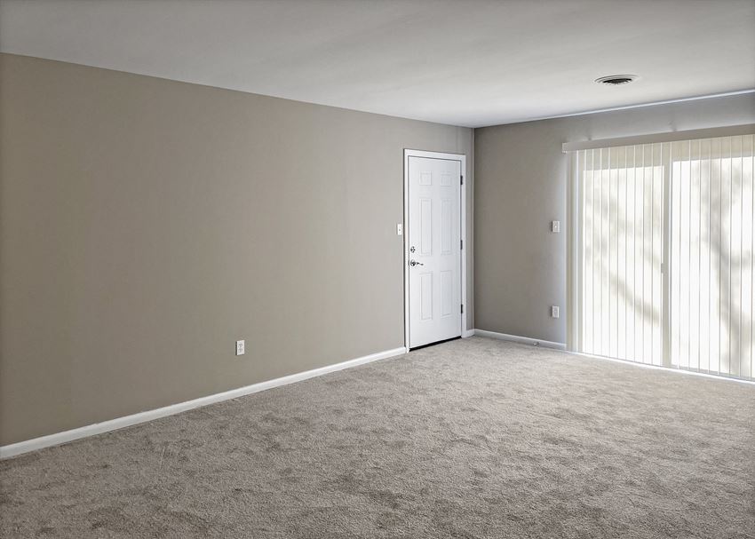 an empty living room with a door and a carpeted floor