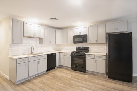 A kitchen with black appliances and white cabinets.
