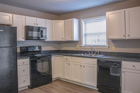 A kitchen with black appliances and white cabinets.