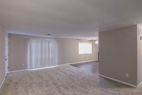 the living room and dining room of an empty house with a white carpet