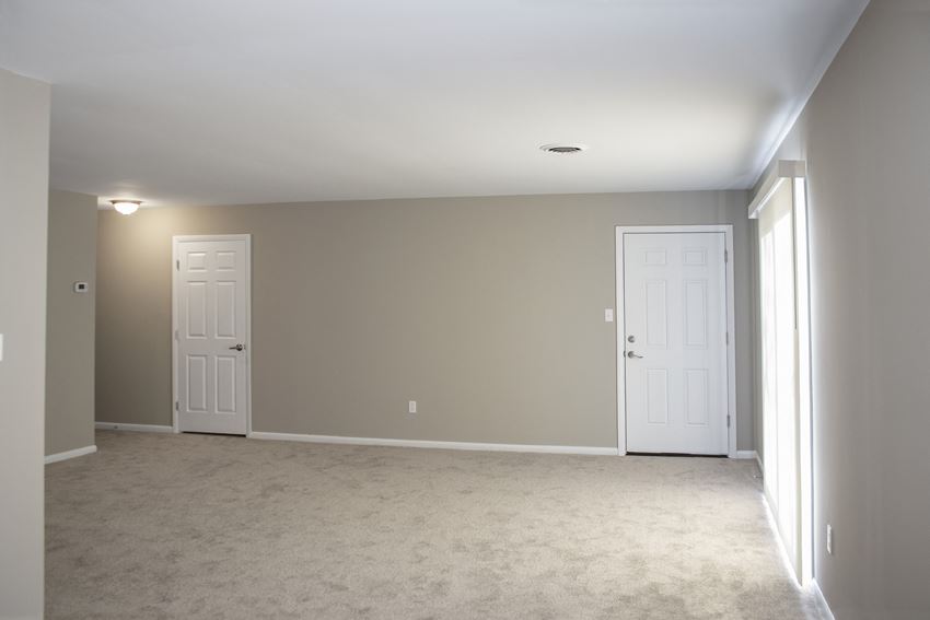 an empty living room with two doors and a carpeted floor