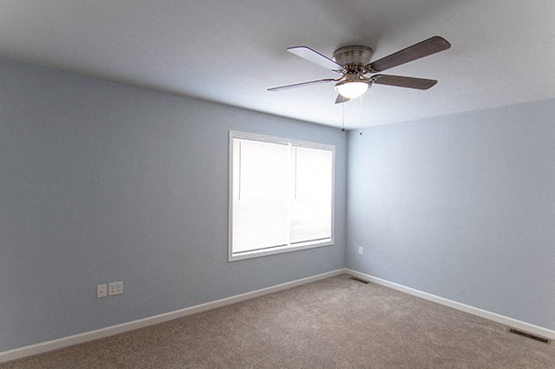an empty room with a ceiling fan and a window