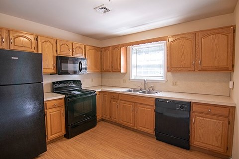 A kitchen with black appliances and wooden cabinets.