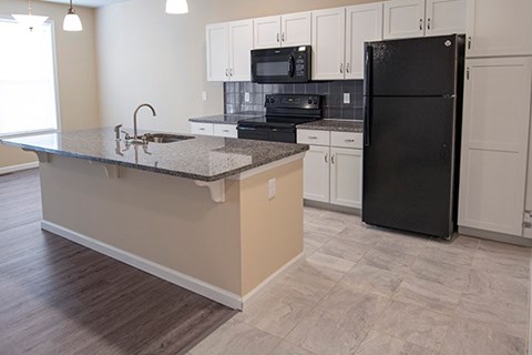 A kitchen with a black refrigerator and white cabinets.