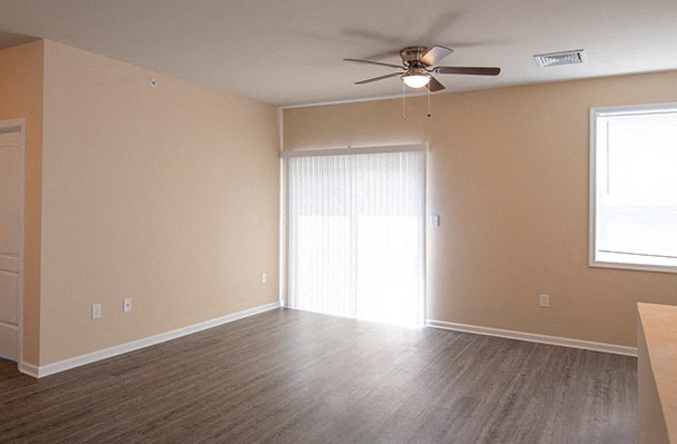 an empty living room with a ceiling fan and a window