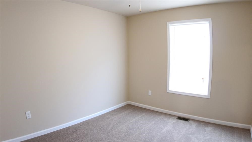 a large empty room with a window and carpet