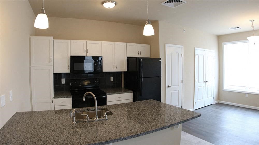 a kitchen with a granite counter top and a black refrigerator