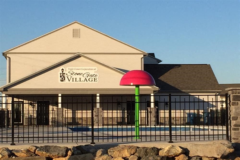 the front of a building with a pool and a fence
