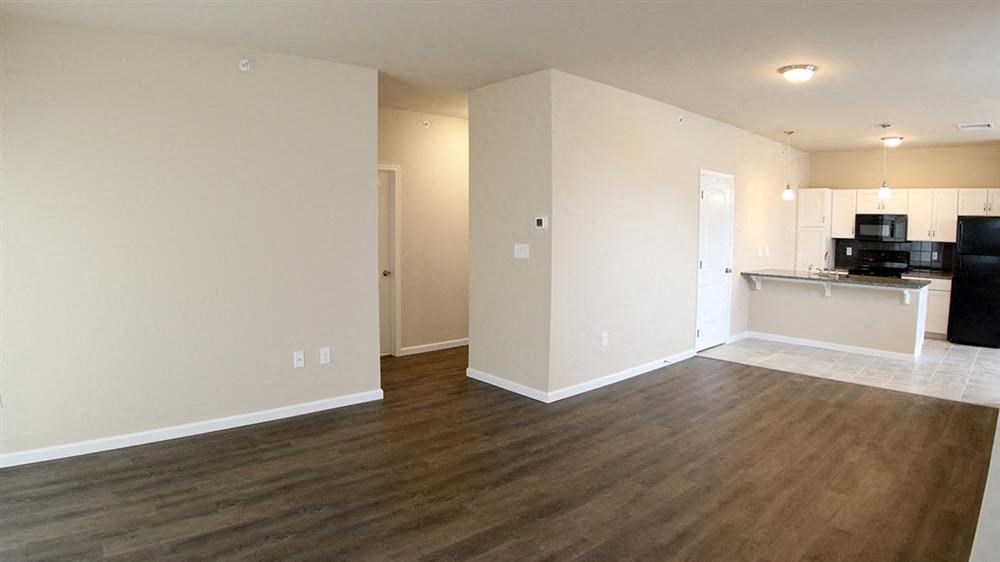 an empty living room and kitchen with a wood floor