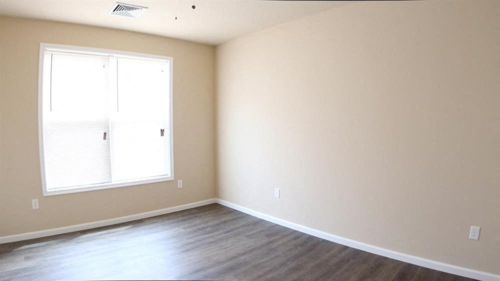 an empty living room with a window and wood floors