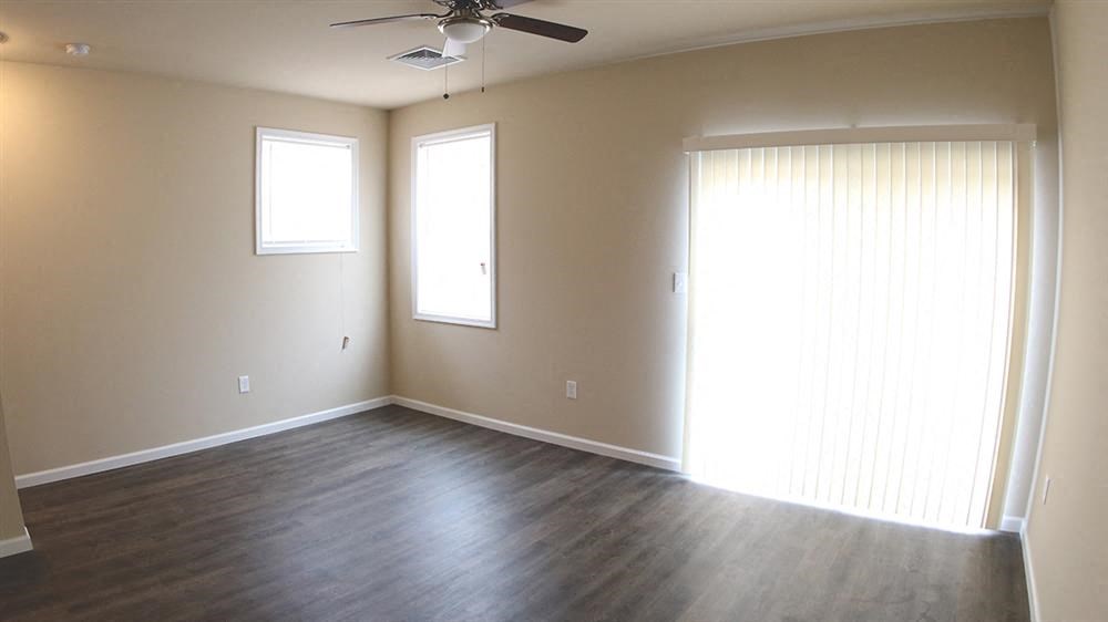 an empty living room with wood floors and a ceiling fan