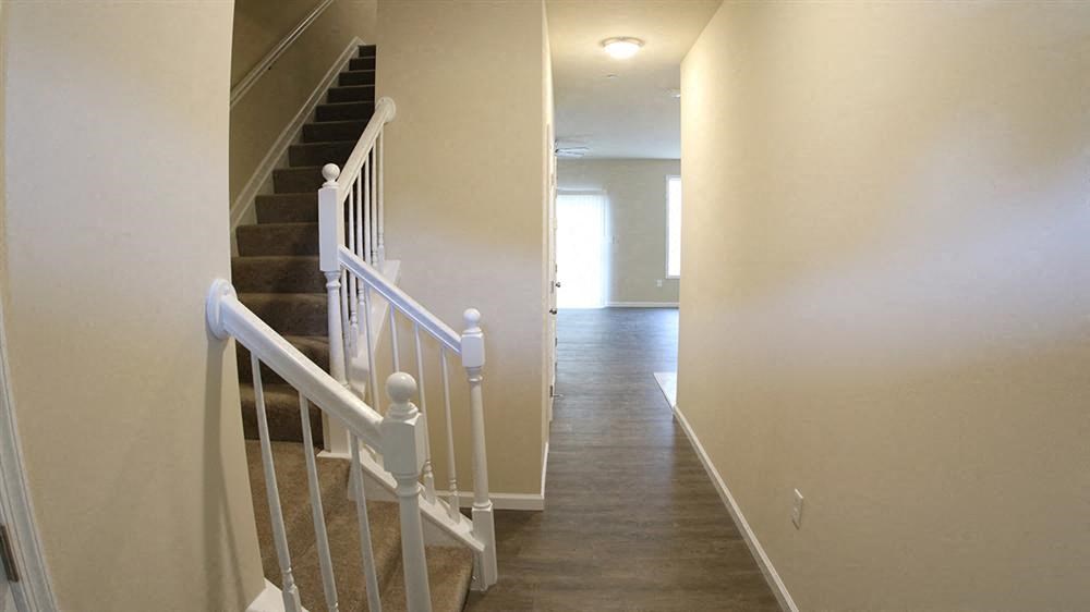 a white staircase in a house with a hallway with stairs
