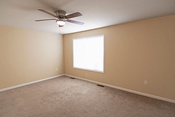 an empty room with a ceiling fan and a window