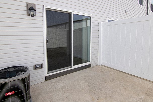the patio of a home with a screen door and a trash can