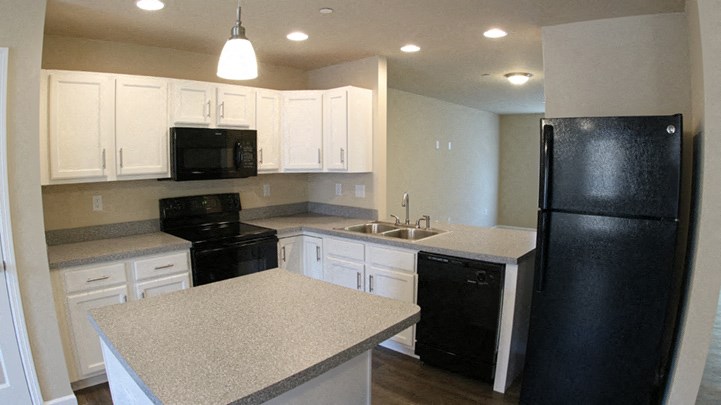 a kitchen with white cabinets and black appliances