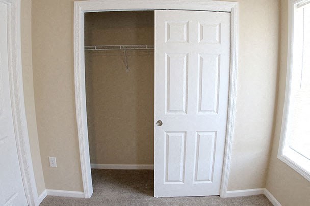 an empty closet with a white door and a window
