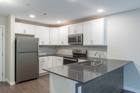 A kitchen with a black counter top and white cabinets.