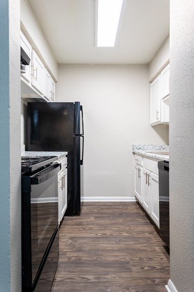 a kitchen with white cabinets and black appliances