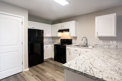 a kitchen with white cabinets and black appliances and a marble counter top