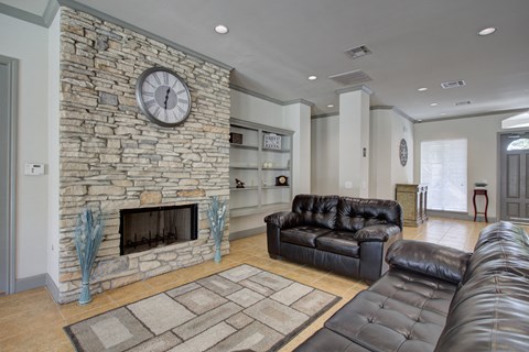 the living room has a large stone fireplace and leather couches