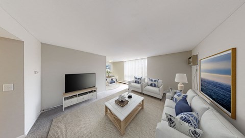 A living room with a white couch, a coffee table, and a painting of a sunset.
