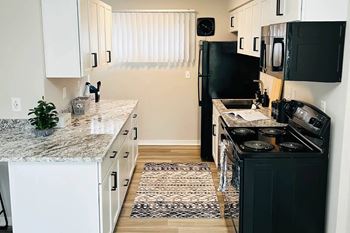 A kitchen with black appliances and white cabinets at Eton Square Apartments and Townhomes, Birmingham