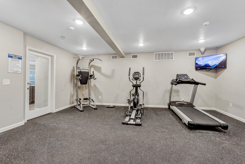 A spacious home gym with a treadmill, elliptical trainer, and stationary bike.
